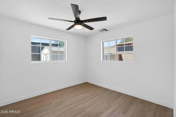 a view of empty room with wooden floor and ceiling fan