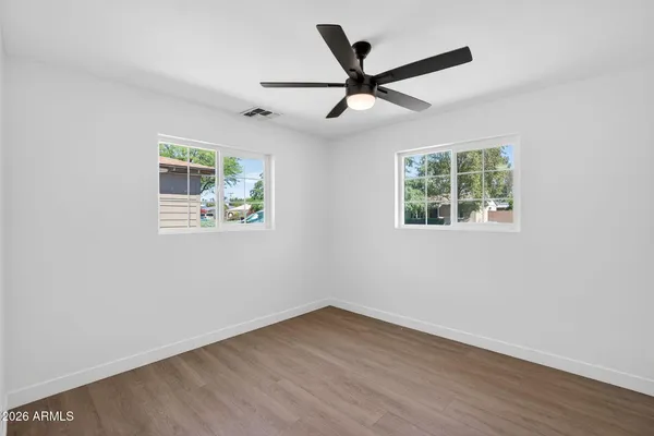 an empty room with wooden floor and windows