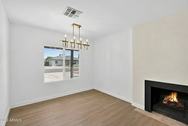 a view of empty room with wooden floor fireplace and chandelier