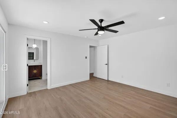 a view of empty room with wooden floor and ceiling fan