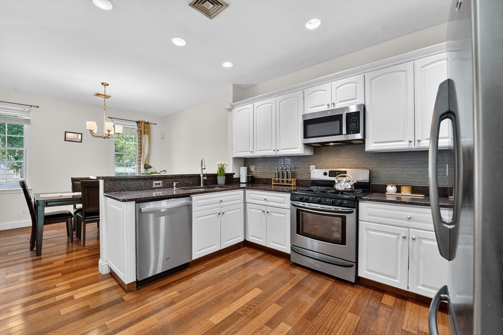 15 Evergreen Circle, Unit 15 Canton, MA 02021 - Photo 11 of 29 a kitchen with stainless steel appliances granite countertop a stove top oven a sink dishwasher and white cabinets with wooden floor
