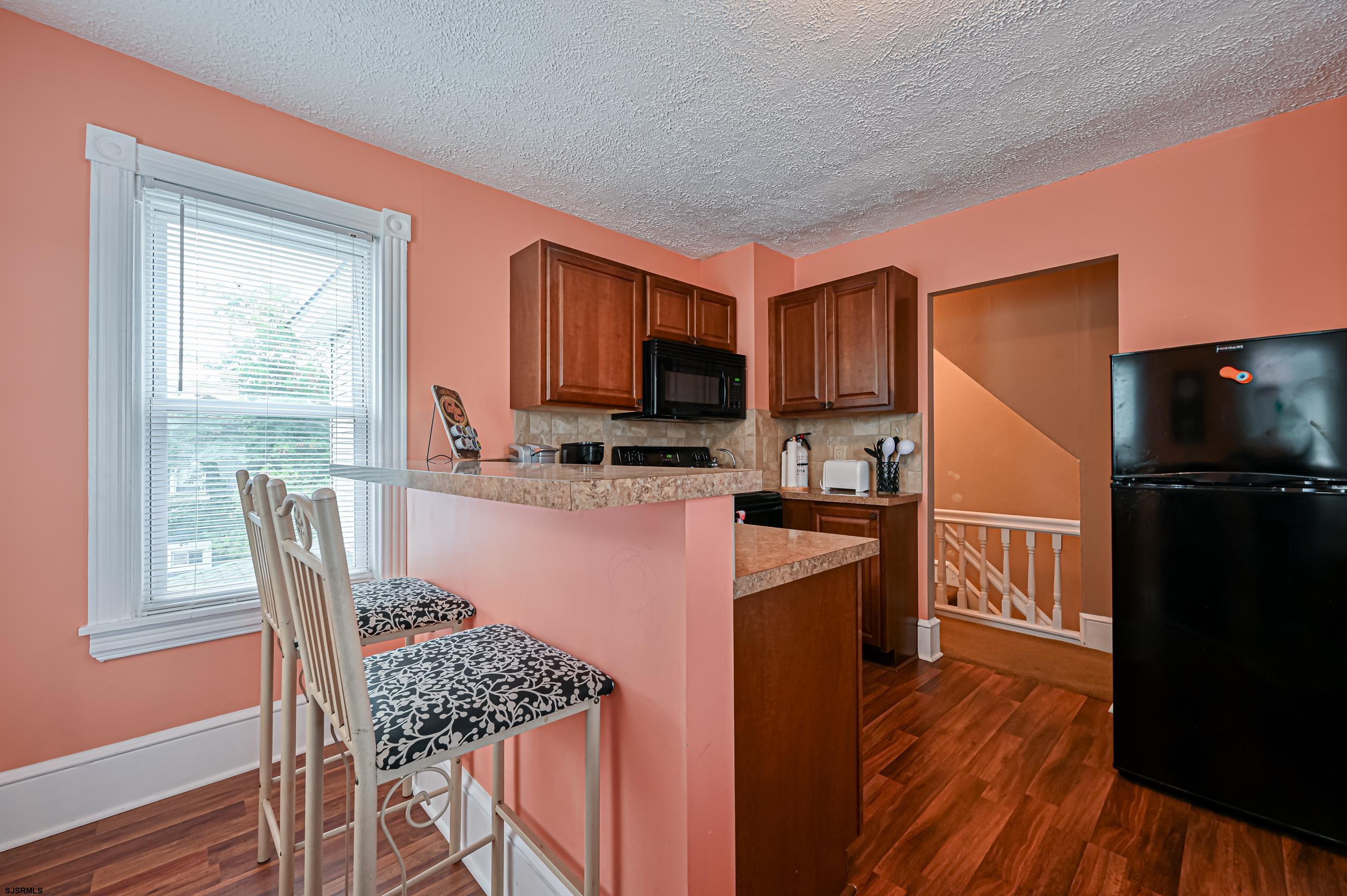 820-822 Shore Somers Point, NJ 08244 - Photo 17 of 27 a kitchen with stainless steel appliances granite countertop a refrigerator a stove top oven a sink dishwasher and wooden cabinets with wooden floor