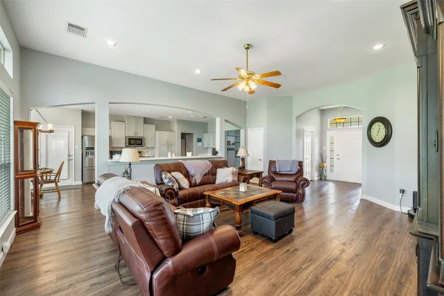 a living room with furniture kitchen view and a wooden floor