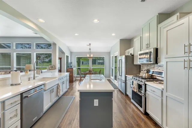 a large kitchen with granite countertop a large counter top stainless steel appliances and windows