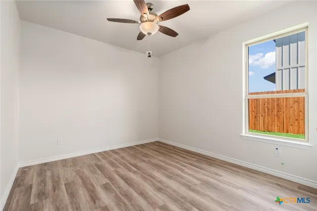 an empty room with a window and a ceiling fan