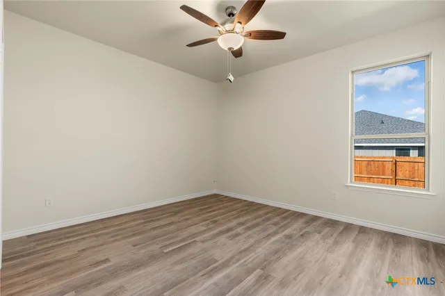 an empty room with a window and a ceiling fan