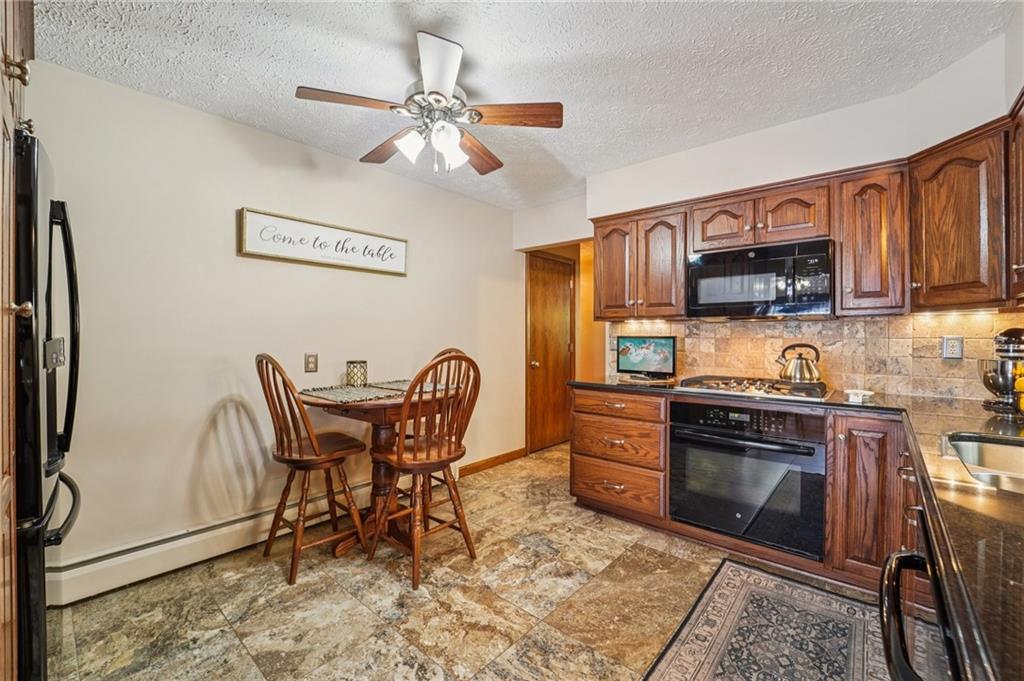 2691 Harlansburg Road New Castle, PA 16101 - Photo 12 of 42 a kitchen with stainless steel appliances granite countertop a stove top oven a sink a dining table and chairs with wooden floor