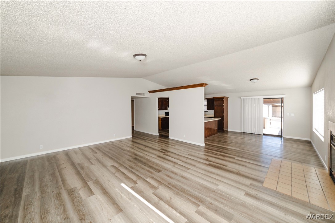 2063 East Sundown Road Kingman, AZ 86409 - Photo 12 of 40 Unfurnished living room featuring a textured ceiling, vaulted ceiling, and light wood-type flooring