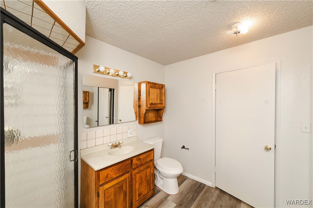 2063 East Sundown Road Kingman, AZ 86409 - Photo 30 of 40 3rd bathroom with wood finished floors, toilet, vanity, tasteful backsplash, and a stall shower