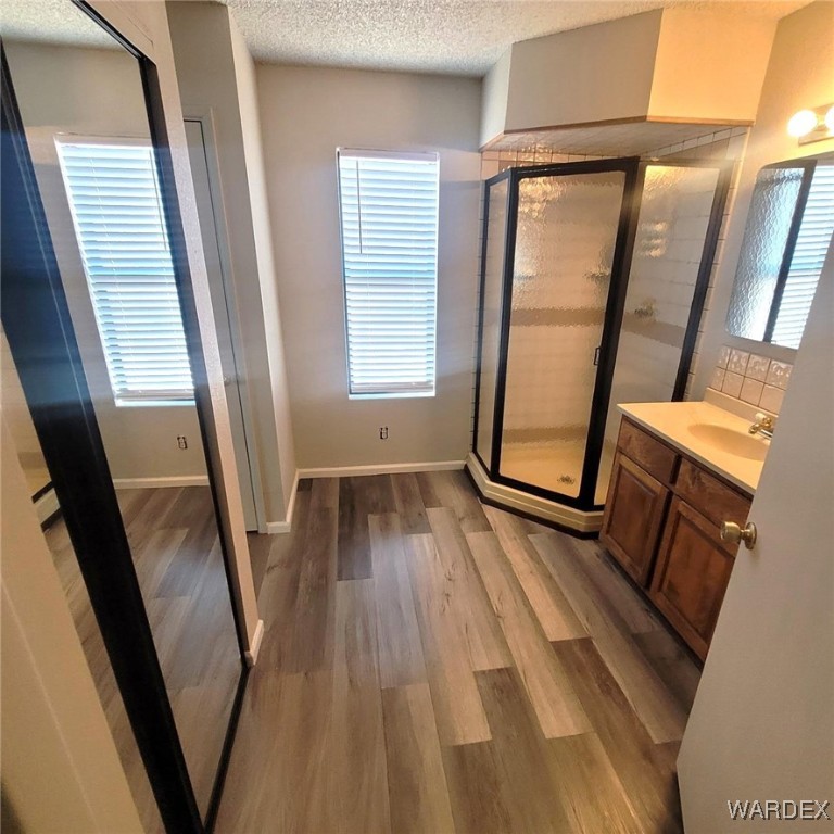 2063 East Sundown Road Kingman, AZ 86409 - Photo 35 of 40 Full bathroom with vanity, baseboards, a shower stall, a textured ceiling, and wood finished floors