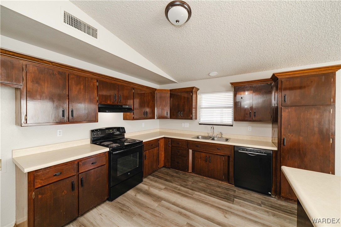 2063 East Sundown Road Kingman, AZ 86409 - Photo 6 of 40 Kitchen featuring lofted ceiling, under cabinet range hood, a sink, visible vents, and black appliances