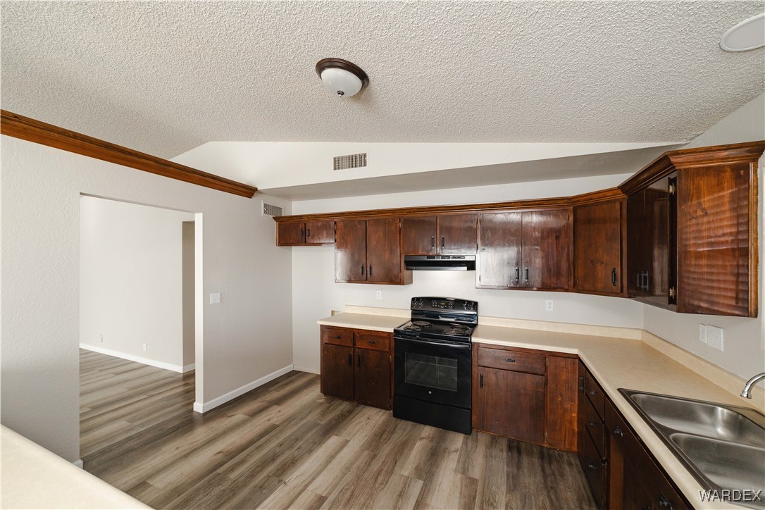 2063 East Sundown Road Kingman, AZ 86409 - Photo 7 of 40 Kitchen featuring black range with electric stovetop, wood finished floors, under cabinet range hood, a sink, and vaulted ceiling