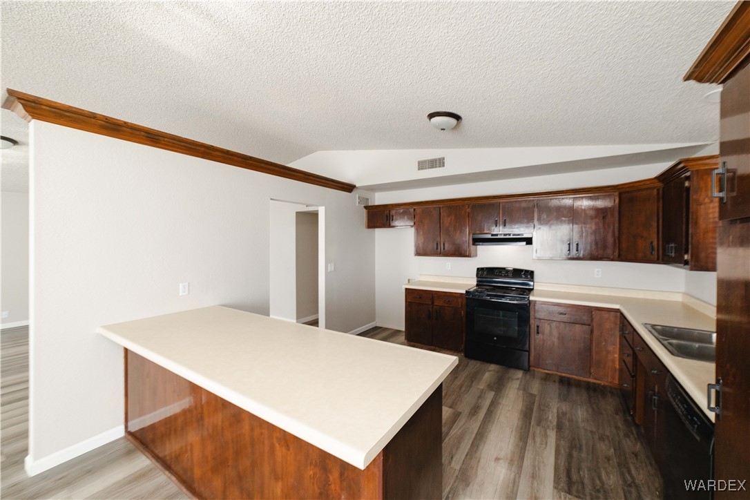 2063 East Sundown Road Kingman, AZ 86409 - Photo 8 of 40 Kitchen with wood finished floors, lofted ceiling, under cabinet range hood, visible vents, and black appliances