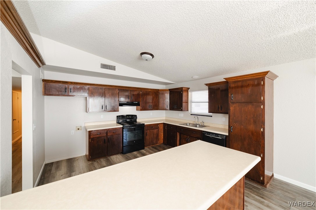 2063 East Sundown Road Kingman, AZ 86409 - Photo 9 of 40 Kitchen featuring light countertops, a sink, ventilation hood, black appliances, and vaulted ceiling