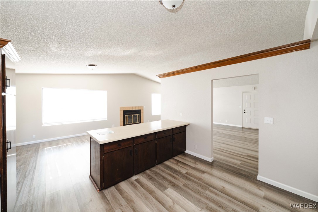 2063 East Sundown Road Kingman, AZ 86409 - Photo 10 of 40 Kitchen featuring light countertops, a peninsula, a fireplace, dark brown cabinets, and light wood-type flooring
