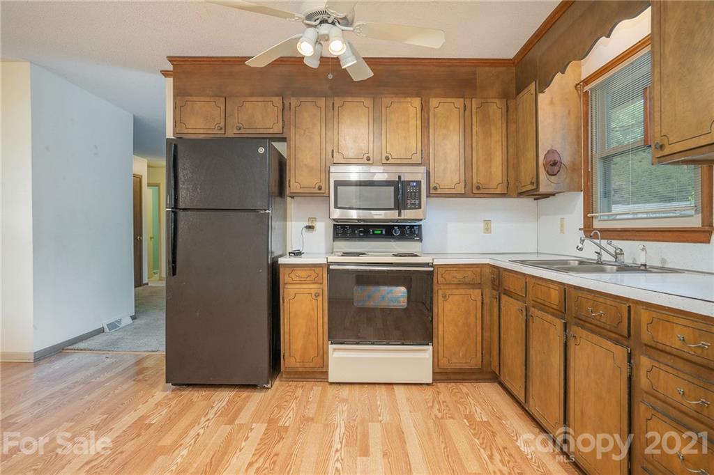 5661 Tuckaseegee Road Kannapolis, NC 28081 - Photo 2 of 18 a kitchen with wooden cabinets a sink a stove a refrigerator and a microwave