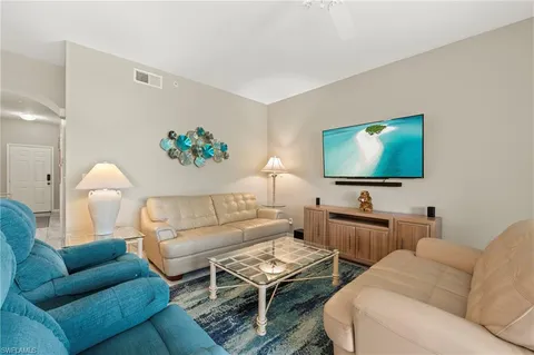 a living room with furniture a flat screen tv and a lamp