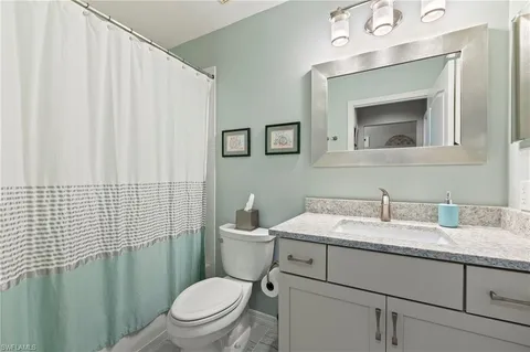 a bathroom with a granite countertop toilet sink and mirror