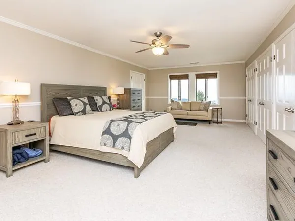 a bedroom with a bed couch chandelier and a window