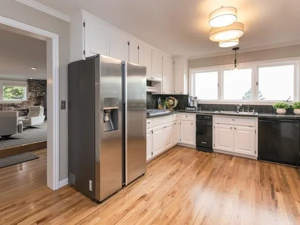a kitchen with stainless steel appliances granite countertop a refrigerator a sink dishwasher a stove and white countertops with wooden floor