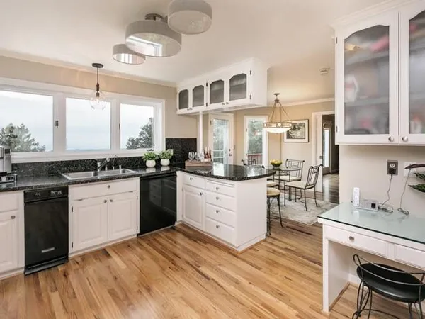 a kitchen with stainless steel appliances granite countertop a stove a sink dishwasher and white cabinets with wooden floor