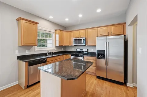 a kitchen with granite countertop a sink a counter top space stainless steel appliances and cabinets