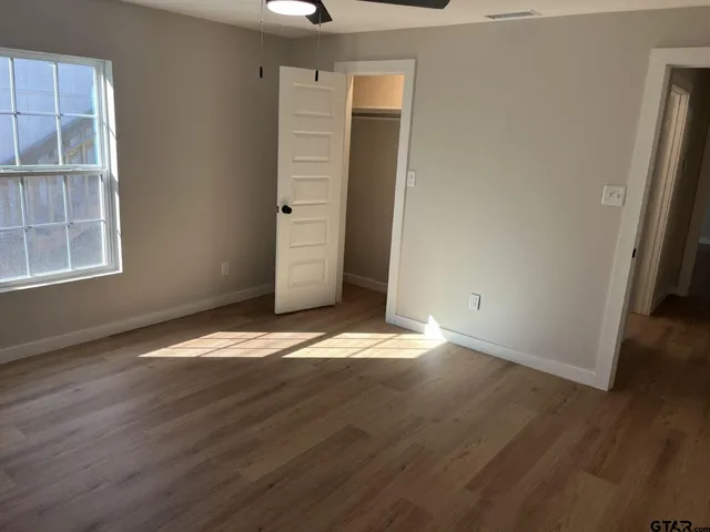 an empty room with wooden floor and windows