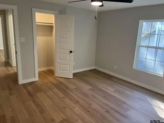 an empty room with wooden floor cabinet and windows
