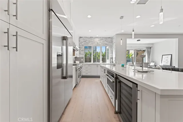 a large white kitchen with a large window and stainless steel appliances