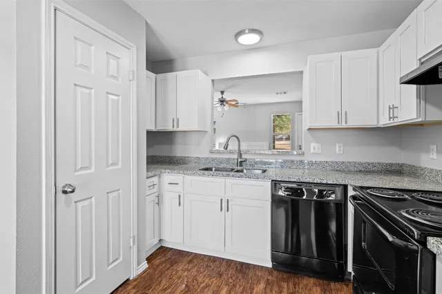 a kitchen with granite countertop a sink stove and cabinets