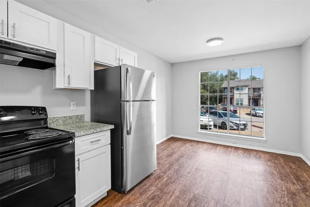 a kitchen with granite countertop a refrigerator stove and microwave