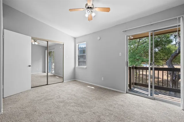 an empty room with windows and ceiling fan