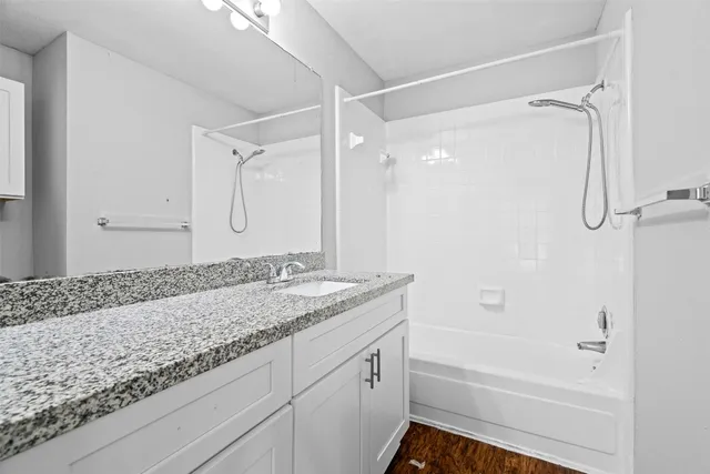 a bathroom with a granite countertop sink mirror vanity and bathtub