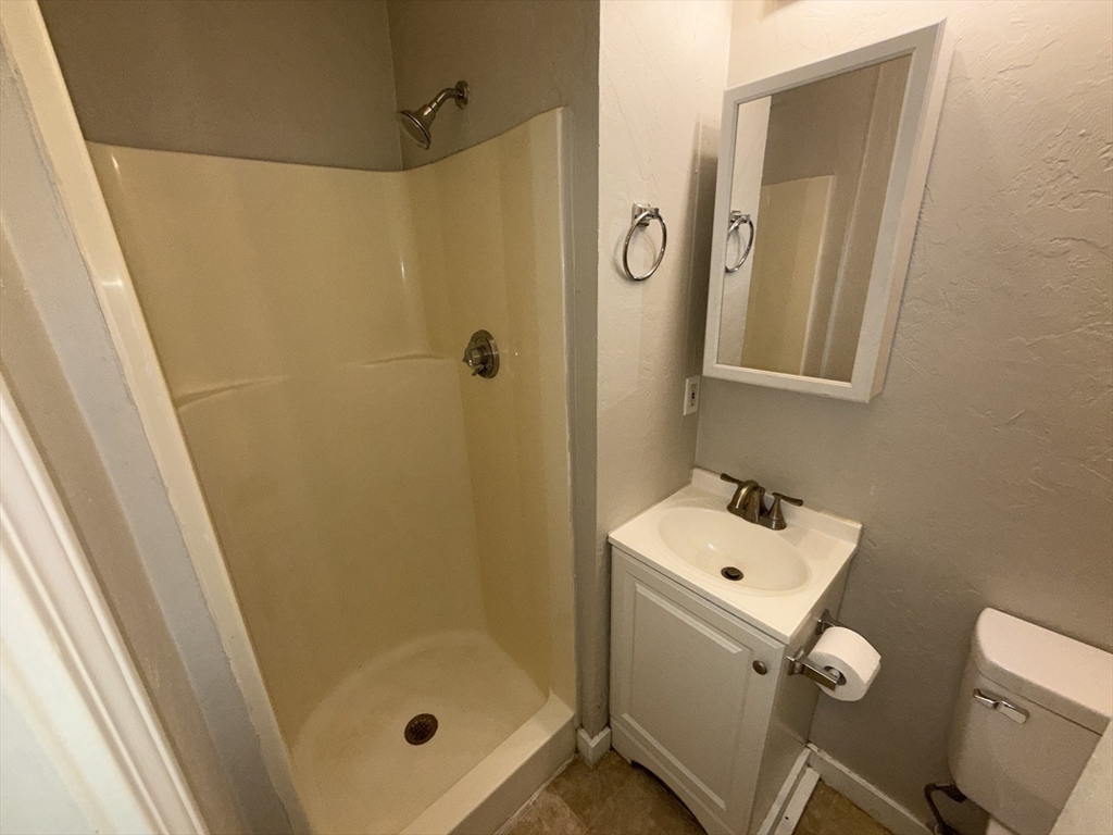 65 Main Street Hudson, MA 01749 - Photo 16 of 20 a bathroom with a shower a sink a toilet and mirror