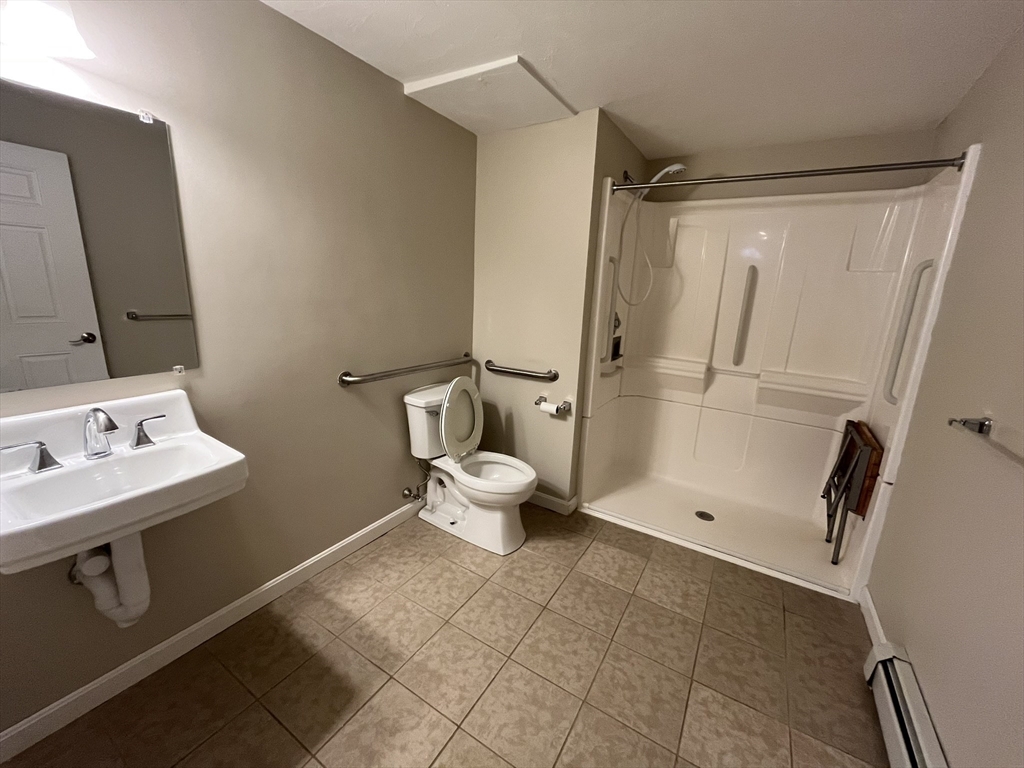 65 Main Street Hudson, MA 01749 - Photo 19 of 20 a bathroom with a sink a toilet a mirror and shower