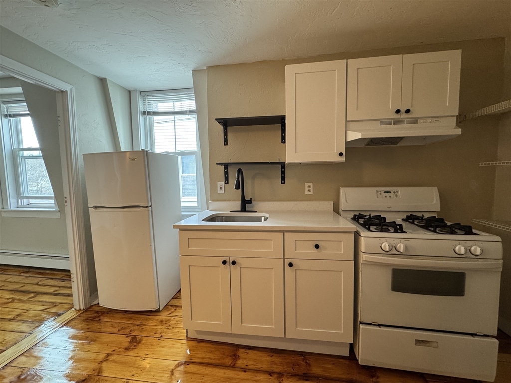65 Main Street Hudson, MA 01749 - Photo 6 of 20 a kitchen with a refrigerator sink stove and cabinets
