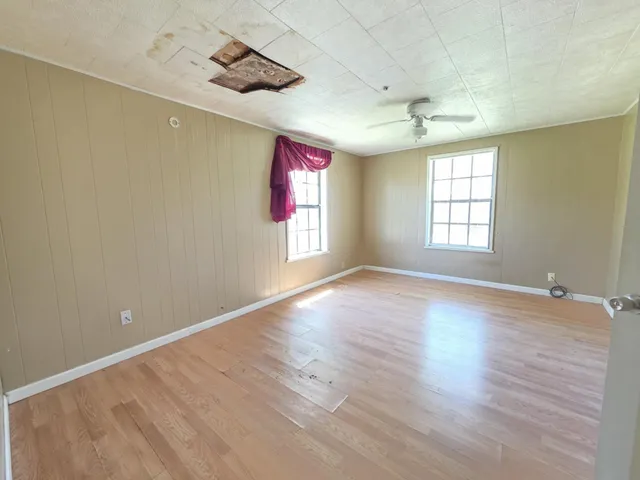 an empty room with wooden floor and windows