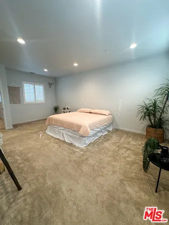 a spacious bedroom with a bed and a potted plant