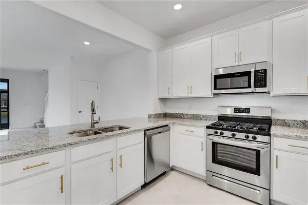 a kitchen with granite countertop white cabinets white stainless steel appliances and a sink
