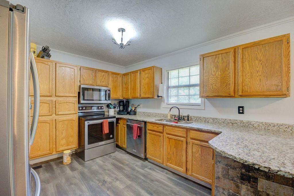 232 Mccadams Road McKenzie, TN 38201 - Photo 5 of 34 a kitchen with stainless steel appliances granite countertop a stove a sink dishwasher a refrigerator and cabinets with wooden floor