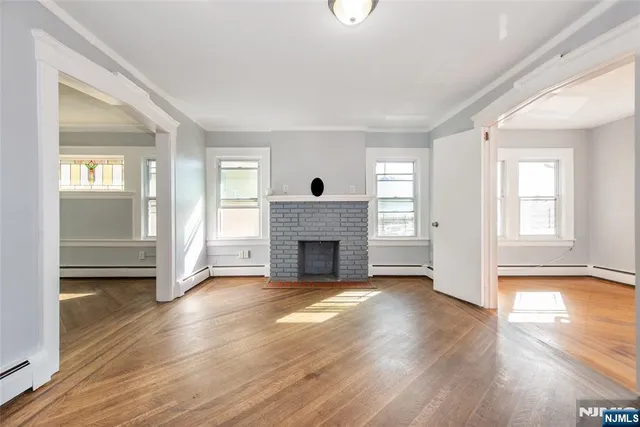 an empty room with wooden floor fireplace and windows