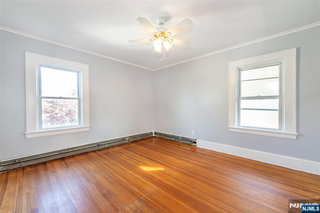 86 Watsessing Avenue, Unit 2 Bloomfield, NJ 07003 - Photo 15 of 23 an empty room with wooden floor chandelier fan and windows