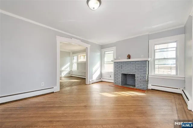 a view of empty room with wooden floor and fireplace