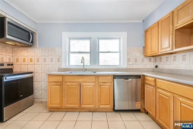 a kitchen with granite countertop cabinets stainless steel appliances a sink and a window