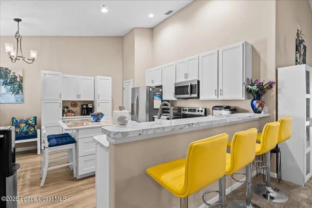 a kitchen with stainless steel appliances granite countertop a table chairs sink and cabinets