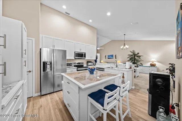a kitchen with a sink stainless steel appliances a refrigerator cabinets and wooden floor