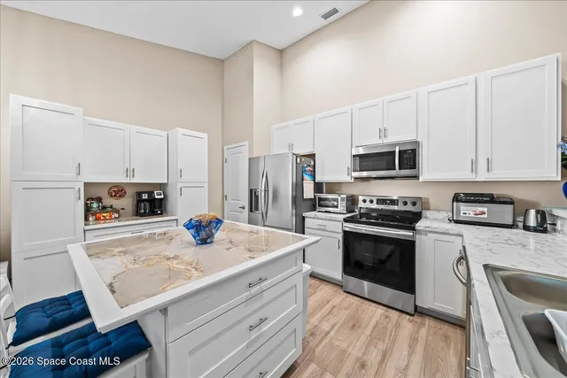 a kitchen with kitchen island a stove a sink and white cabinets