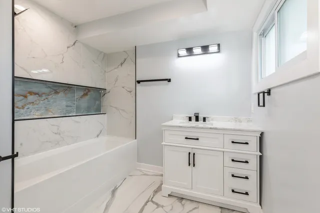 a bathroom with a bathtub sink vanity and mirror