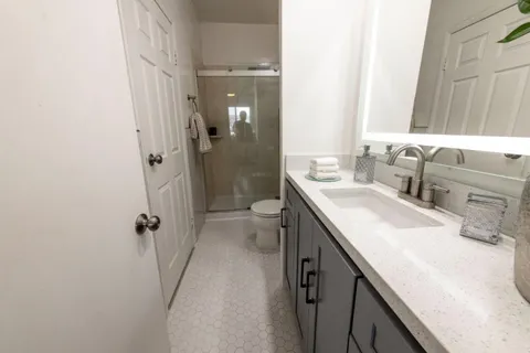 a bathroom with a granite countertop sink a mirror and a toilet