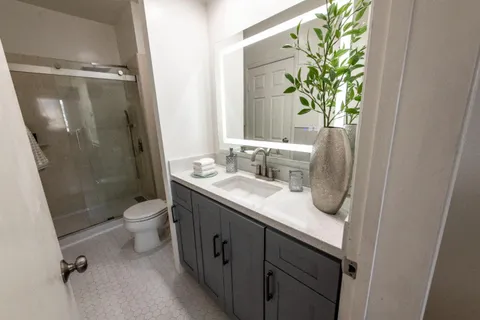a bathroom with a granite countertop sink a toilet and a shower